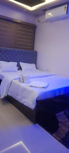 a bedroom with a bed with a blue headboard at Hotel Hangout in Jangipur