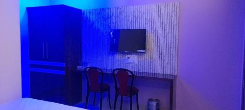 a room with two chairs and a table with a tv at Hotel Hangout in Jangipur