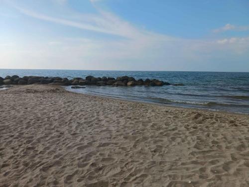 a sandy beach with rocks in the water at Lovely Summer House With Spa, Close To The Beach in Vejby