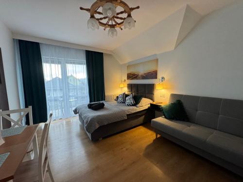 a bedroom with a bed and a couch and a chandelier at Złote Piaski Pensjonat z basenem in Darłowo