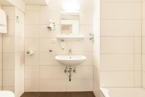 a white bathroom with a sink and a mirror at Novum Hotel Ahl Meerkatzen Köln Altstadt in Cologne