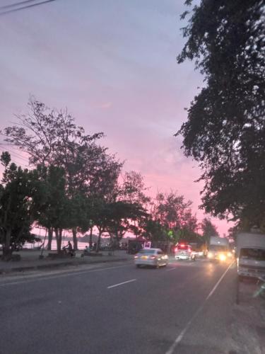a street with cars driving down the road at sunset at New Well House Apartment in Weligama