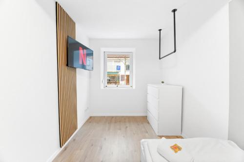 Una habitación blanca con una cama y un televisor. en Gemütliches Haus in Nürtingen Zentrum Kitchen,Wifi,Smart TV, en Nürtingen