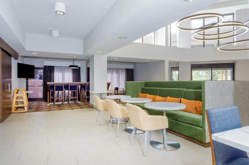 a living room with a green couch and tables and chairs at Hampton Inn Jacksonville - I-95 Central in Jacksonville