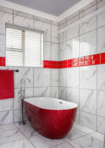 a red bath tub in a bathroom with red accents at SelaMod Village Guest House in Tshaneng