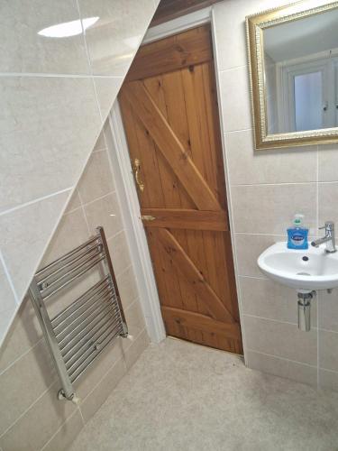 a bathroom with a wooden door and a sink at Hereford - Falcon House - Spacious 5 Bedroom House With Games Room - Sleeps 14 Guests - Great Property For Family & Friends Gathering Together - Hosted by RENTMYHOUSE in Hereford