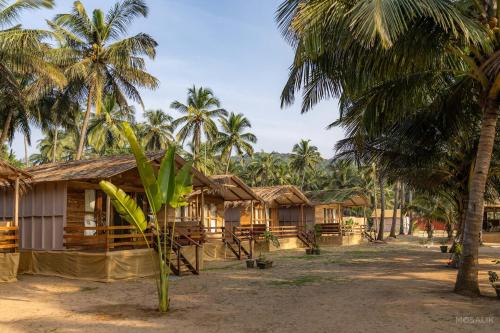 a row of wooden houses in front of palm trees at Ravi Yoga Retreat in Polem