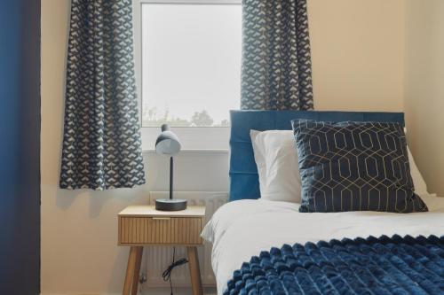 a bedroom with a bed with blue curtains and a window at St Abbs - Beautiful Home, EV, parking, garden in Hull