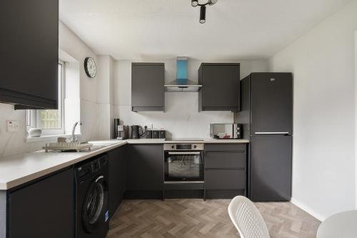 a kitchen with black cabinets and a dishwasher at St Abbs - Beautiful Home, EV, parking, garden in Hull