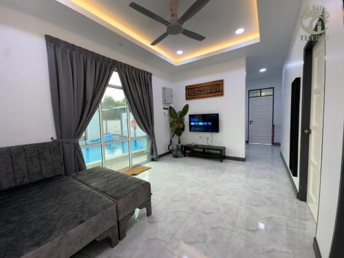 a living room with a couch and a tv at The Gelam House in Kampong Telaga Papan