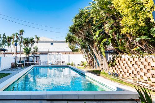 a swimming pool in a yard with palm trees at Cape Town Milnerton Lagoon Villa in Cape Town