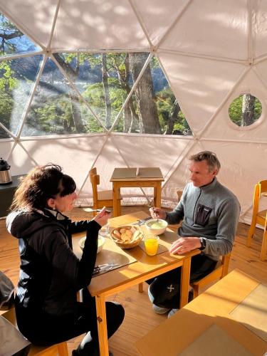 a man and woman sitting at a table in a yurt at FITZ CAMP - Glamping agreste - Base Cerro Fitz Roy in El Chalten