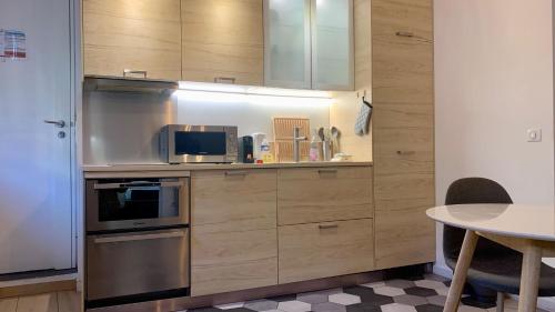 - une cuisine avec des placards en bois, un four micro-ondes et une table dans l'établissement ApartHotel Riviera - ISTRIA 1- Old town Promenade des Anglais - Superbe Appartement Superior 2 Pièces AC, à Nice
