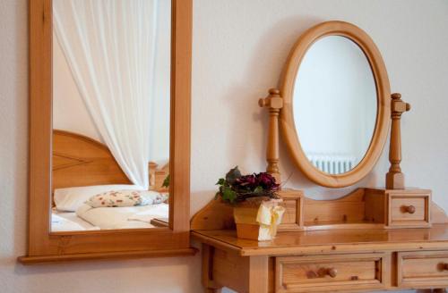 a mirror on a wooden stand next to a bed at Haus Schlesien in Königswinter
