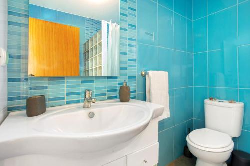 Un baño con azulejos azules, lavabo e inodoro. en The Wave House - Two Bedroom Flat, en Jardim do Mar