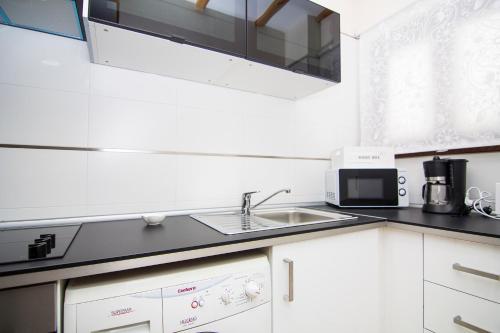 a white kitchen with a sink and a microwave at Apartamentos Centro Puerto de Santa Maria in El Puerto de Santa María