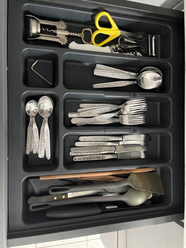 un tiroir noir rempli d'ustensiles et de ciseaux dans l'établissement Le Roch - T3 Cosy & Spacieux, à Amiens