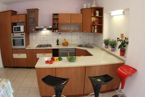 a kitchen with wooden cabinets and a counter with stools at Apartments Giardino in Hvar