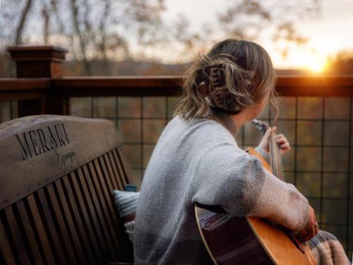a woman sitting on a chair playing a guitar at Meraki Escape in Brevard