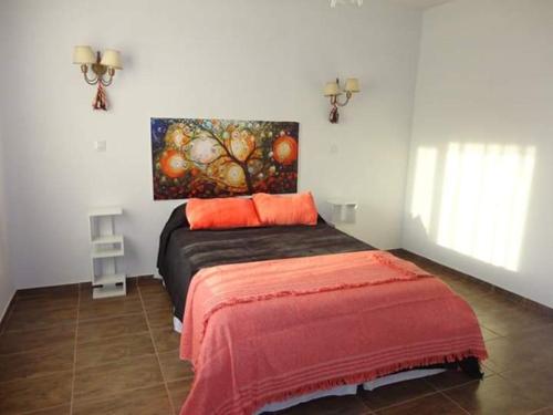 a bedroom with a bed with a painting on the wall at CABAÑAS DEL ANGEL in Capilla del Monte
