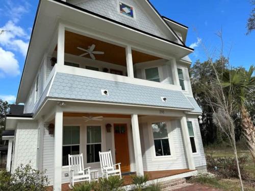 a white house with two white chairs on the porch at Gator Grove - Queen Ann White - New Build! in Gainesville