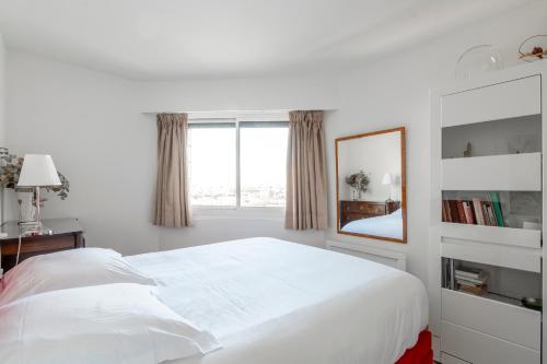 une chambre blanche avec un grand lit et un miroir dans l'établissement Veeve - Panoramic Views from the 17th, à Paris
