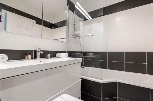 une salle de bain blanche avec un lavabo et un miroir dans l'établissement Veeve - Panoramic Views from the 17th, à Paris