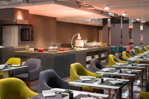 a restaurant with tables and chairs and a kitchen at Aloft Jakarta Wahid Hasyim in Jakarta