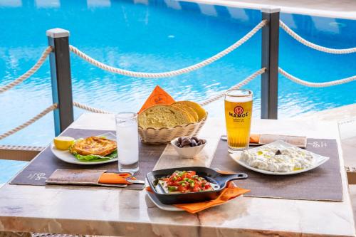 a table with two plates of food and a glass of beer at Nereides Hotel in Karpathos Town