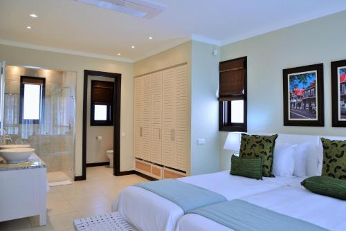 a bedroom with a white bed and a bathroom at Eden Island Luxury Accommodation in Eden Island