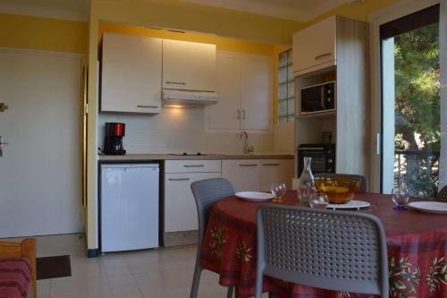 une cuisine avec des armoires blanches et une table avec des chaises dans l'établissement Appartement deux pièces - Argelès sur mer - AR110-007, à Argelès-sur-Mer