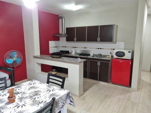 a kitchen with a table and a red wall at Hermoso Departamento en Quines in Quines