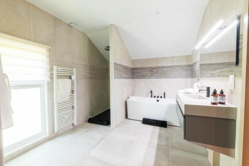 a bathroom with a white tub and a sink at L'Artbanne - Le domaine in Saint-Hilaire-le-Petit