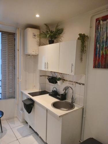 - une cuisine avec un évier et des placards blancs dans l'établissement Chambre proche centre et monuments, à Paris