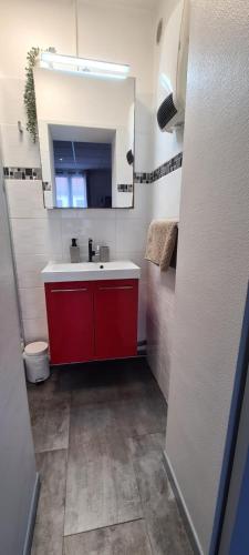 une petite cuisine avec une armoire rouge et un évier dans l'établissement L'Urban Clignancourt - Bel appartement tout équipé aux Portes de Paris, à Saint-Ouen