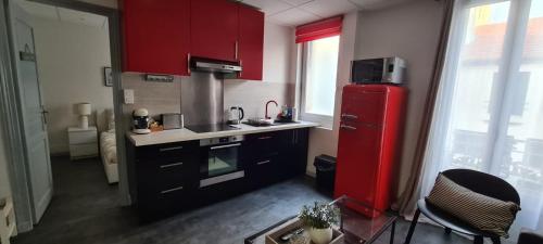 Il comprend une cuisine équipée de placards rouges et d'un réfrigérateur rouge. dans l'établissement L'Urban Clignancourt - Bel appartement tout équipé aux Portes de Paris, à Saint-Ouen