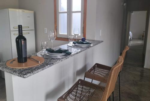 a table with a bottle of wine and two chairs at Relax MDZ - Memorable Apt in Godoy Cruz