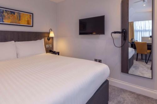 a hotel room with a bed and a mirror at Best Western Kensington Olympia Hotel in London