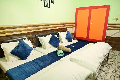 a bed with blue and white pillows and a red door at vaidehi homlee premium stay, 3kms from Shri Ram janmbhoomi, Ayodhya in Faizābād