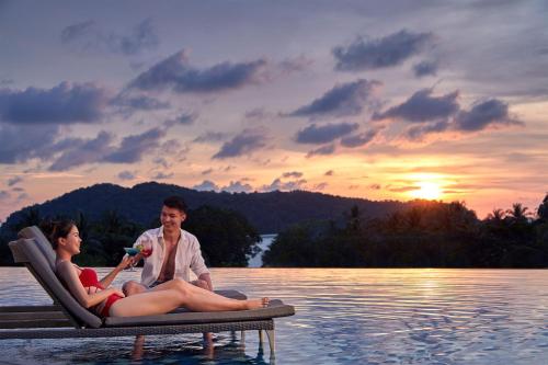 a man and a woman sitting on a raft in the water at Aloft Langkawi Pantai Tengah in Pantai Cenang