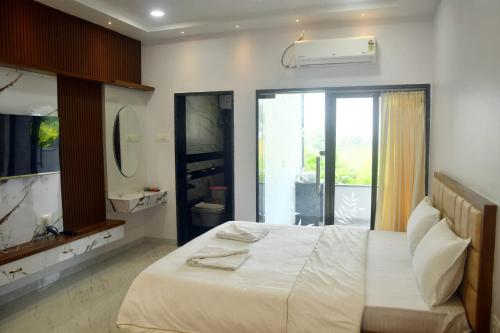 a bedroom with a large white bed and a bathroom at Ajanta hill resort fardapur in Phardāpur
