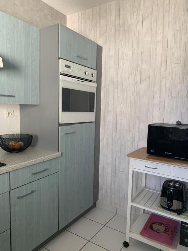 une cuisine avec des armoires bleues et un four à micro-ondes dans l'établissement Les Clarisses, à Saint-Gilles-Croix-de-Vie