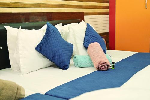 a bed with blue and white pillows on it at vaidehi homlee premium stay, 3kms from Shri Ram janmbhoomi, Ayodhya in Faizābād
