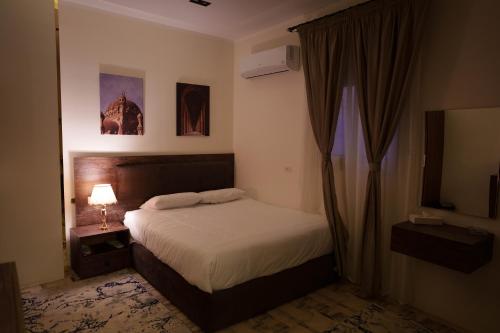a bedroom with a bed and a lamp and curtains at Pyramids Sunshine View in Cairo