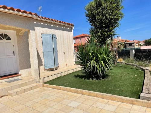 a house with a green yard with a door at Maison 3 chambres - 8 personnes - Elne - AR000-E12 in Elne
