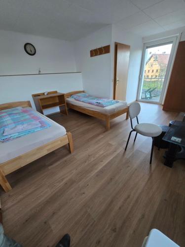 a room with two beds and a table and a chair at Pension Hirsch in Berg