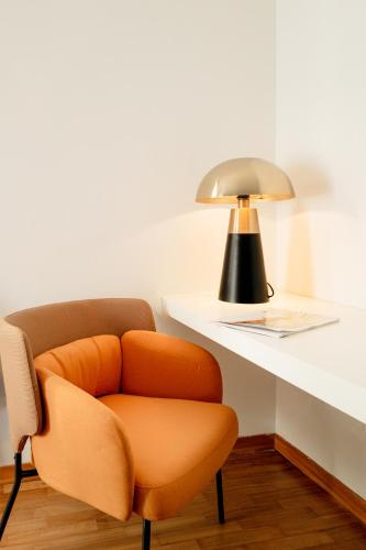 an orange chair sitting next to a desk with a lamp at Albereto 41 in Calenzano