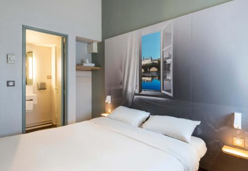 a bedroom with a large white bed with two pillows at B&B HOTEL Laval Changé in Changé