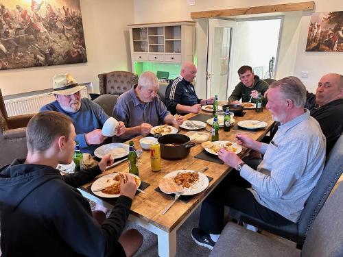a group of men sitting around a table eating pizza at Forces Manor in Kincraig