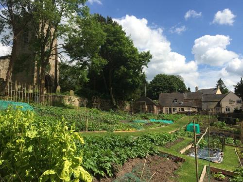 a garden with vegetables and a church in the background at The White Hart Apartment Valley View in Alton